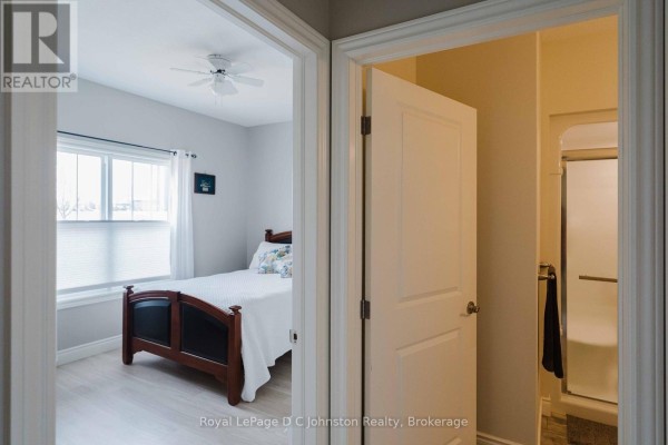 View into a bedroom with a double bed and a doorway to a bathroom with a shower. - 1062 Waterloo Street, Saugeen Shores