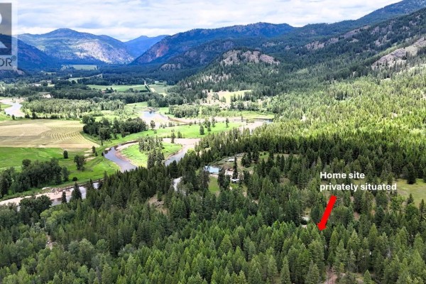 Aerial view of a remote cabin site marked with a red arrow, situated privately among abundant trees with mountain views. - 10625 Granby Road Lot# 1, Grand Forks