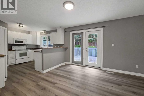 View into a room with light gray wood-look flooring and neutral walls. - 10629 104 Avenue, Grande Cache