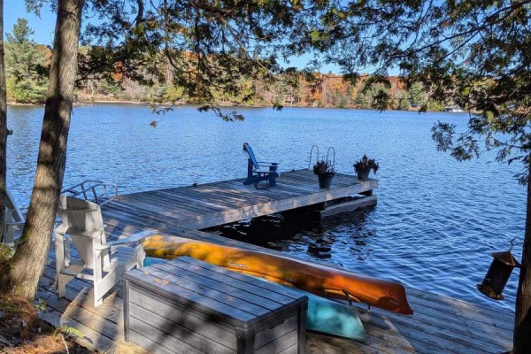 View of the lake from an Adirondack chair, surrounded by trees - 1063 Whiteside Road, Muskoka Lakes