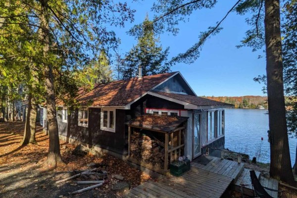 Side view of the cottage showing windows and chimney, surrounded by trees - 1063 Whiteside Road, Muskoka Lakes