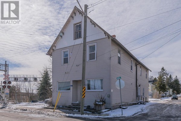 Side exterior of a two-story light beige multi-family home with a steep gable roof. - 1064 Prince Street, Lansdowne Village