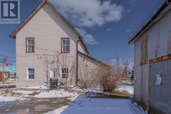 Side and rear exterior of a light beige home with vinyl siding and a detached structure. - 1064 Prince Street, Lansdowne Village