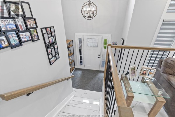 Interior view of the foyer with a staircase, white front door, and gallery wall. - 1067 Maple, Kingsville