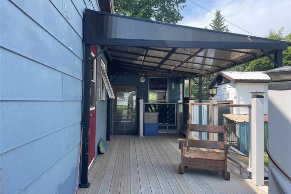 Wooden deck with a clear covered roof and a simple wooden chair. - 1067 St. Clare Street, Birtle