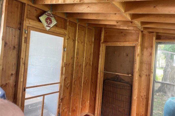 Interior of a screened-in porch with wood paneling and two doors. - 1067 St. Clare Street, Birtle