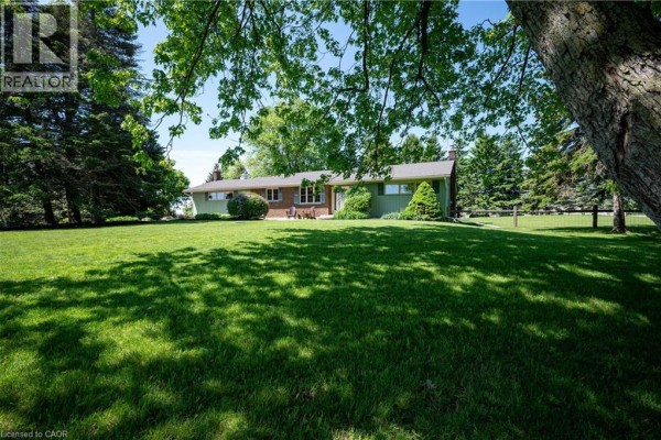 Front view of a single-story house with green siding and a brick base. - 1068 Cameron Road, Ayr
