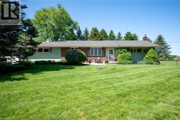 Exterior view of the ranch-style house with green siding and brick accents. - 1068 Cameron Road, Ayr