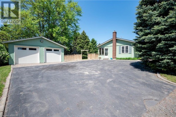 Detached two-car garage and a small cottage-style house with a chimney. - 1068 Cameron Road, Ayr