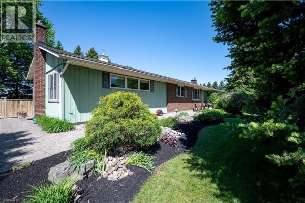 Close-up of the house exterior with landscaping, stone path, and mulch beds. - 1068 Cameron Road, Ayr