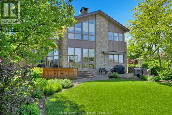 Stone patio with two Adirondack chairs and a small table surrounded by gravel and landscaping. - 10691 Lakeview Drive, Chatham Kent
