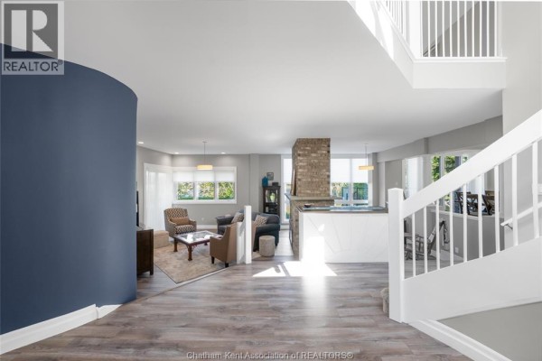Cozy loft area with a plaid sofa, chess table, and large windows offering a lake view. - 10691 Lakeview Drive, Chatham Kent