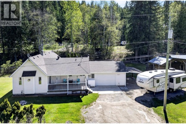 Aerial view of a lakefront with a dock, beach, and buildings, surrounded by forested mountains. - 106e Old N Thompson Highway, Clearwater