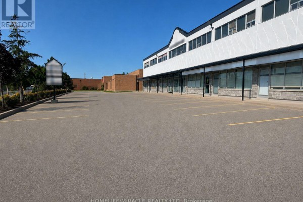 Commercial building exterior with a large asphalt parking lot. - 107 - 1339 Khalsa Drive, Mississauga