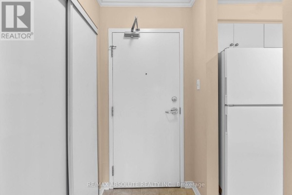 Apartment interior hallway showing a closed white door and a white refrigerator. - 107 - 16 Sheffield Street, Arnprior