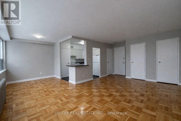 Living room with parquet floors, grey walls, and access to kitchen. - 107 - 42 Thorncliffe Park Drive, Toronto