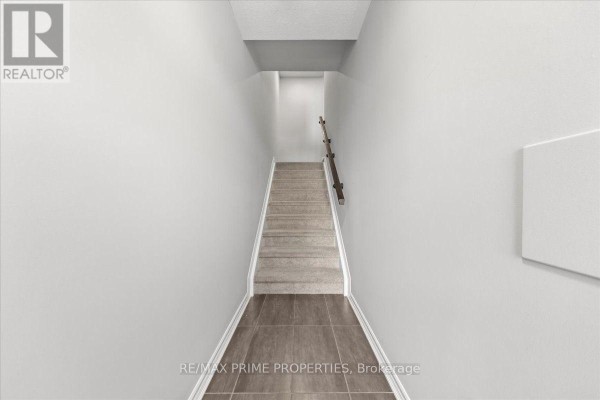 Looking down a carpeted staircase with light grey walls and a wooden handrail. - 107 - 657 Makwa Private, Ottawa
