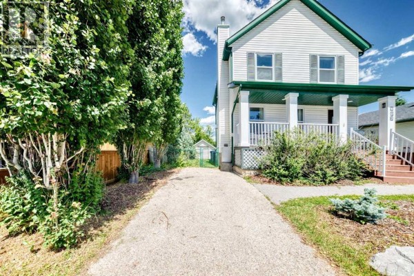 Aerial view of a two-story white house with a green roof and porch. - 107 2a Avenue Nw, Diamond Valley