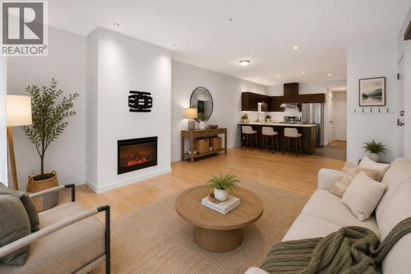 Living room with a fireplace, light wood floors, and a sofa. - 107 40147 Government Road, Squamish