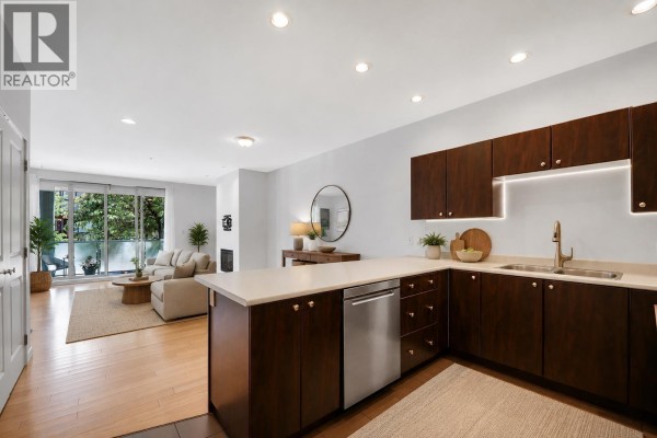 Modern kitchen with dark wood cabinets, a large island, and stainless steel appliances. - 107 40147 Government Road, Squamish