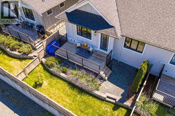 Modern kitchen with a large island, stainless steel refrigerator, and range. - 107 4098 Buckstone Rd, Courtenay