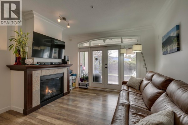 Living room with fireplace, large TV, and access to outdoor space - 107 976 Adair Avenue, Coquitlam