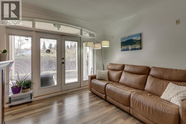 Cozy living area featuring leather sofa and natural light from double doors - 107 976 Adair Avenue, Coquitlam