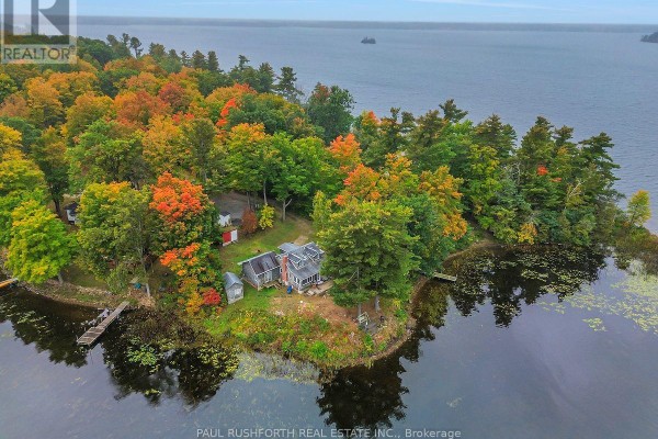 Aerial view of the property featuring a house nestled among colorful autumn trees on a peninsula. - 107 Beck Shore Road, Drummond/north Elmsley