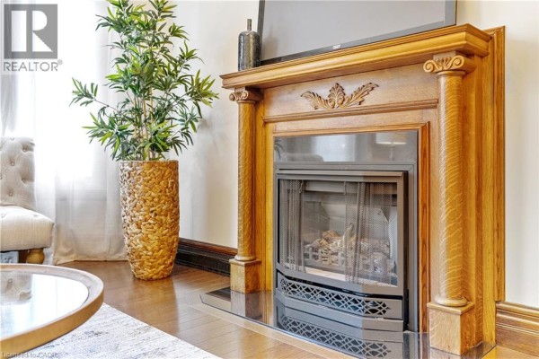 Close-up of a wooden fireplace mantel with decorative carvings surrounding a gas fireplace. - 107 Catharine Street S Unit# Main Flr, Hamilton