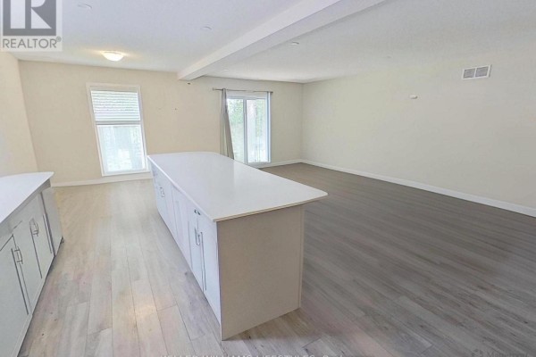 Modern kitchen with large island, white cabinets, and wood flooring - 107 Cavendish Crescent London North