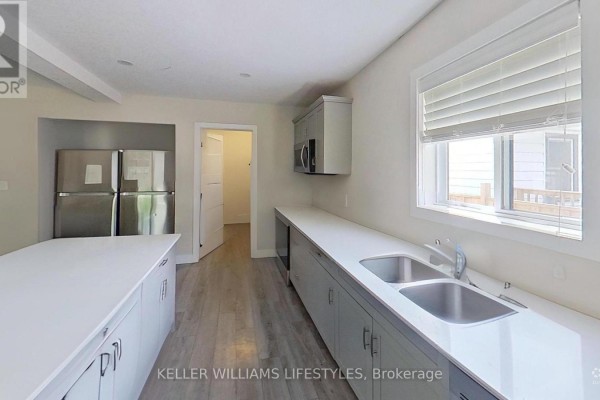 Kitchen area with light grey cabinets, stainless steel appliances, and a double sink. - 107 Cavendish Crescent, London North