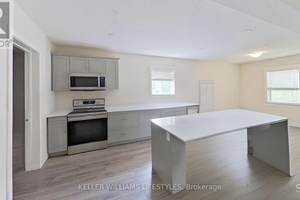 Open-concept kitchen and living area with a large white island and light grey cabinets. - 107 Cavendish Crescent, London North