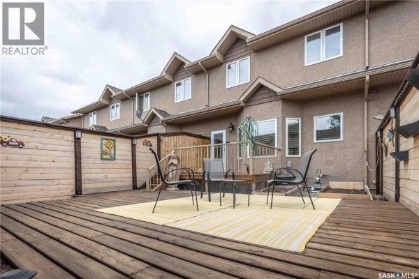 Backyard deck area with chairs and a table, enclosed by wood fencing. - 107 Galloway Road, Saskatoon