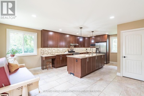 Spacious kitchen with dark wood cabinets, a large island, and stainless steel appliances. - 107 George Street, Clearview
