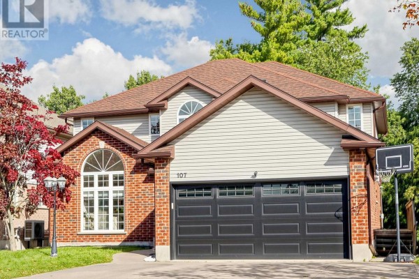 Close-up of the front of a two-story brick and vinyl siding house with a dark garage door and a basketball hoop. - 107 Green Bank Drive, Cambridge