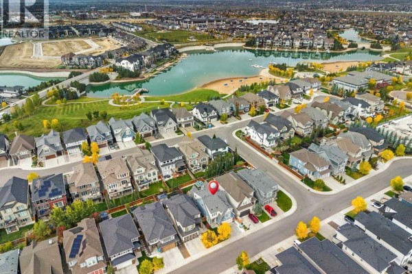 Aerial view of a suburban neighborhood with houses surrounding a lake and park. - 107 Masters Way Se, Calgary