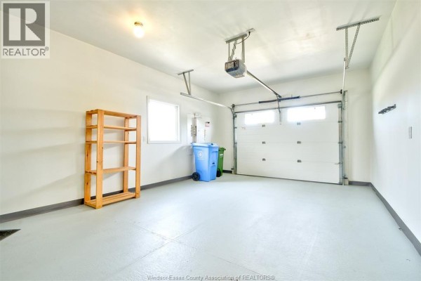 Interior of a clean, spacious two-car garage with white overhead doors and shelving. - 107 Meadowview, Amherstburg