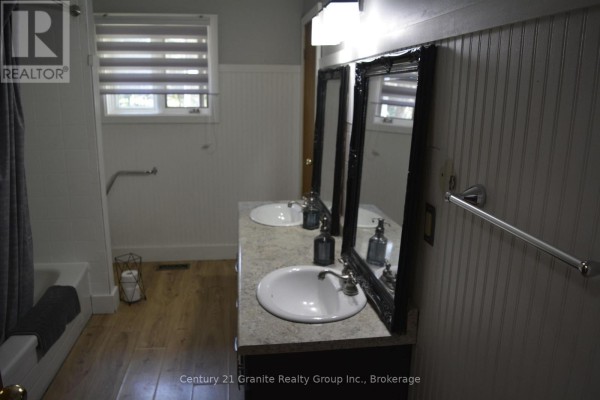 Bathroom with a double vanity, two sinks, mirrors, bathtub and light wood laminate flooring. - 107 South Baptiste Lake Road, Hastings Highlands