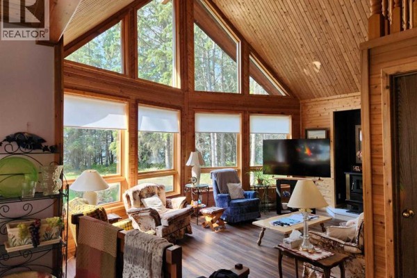 Living room with high vaulted wood ceiling, large windows, and wood paneling. - 107 Spruce Crescent, Brightsand Lake