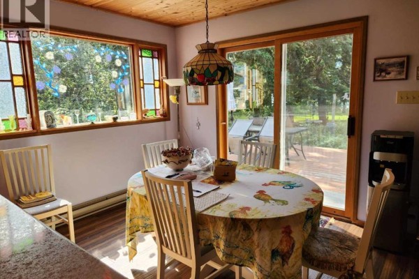 Dining area with a round table, chairs, and sliding glass doors to a deck. - 107 Spruce Crescent, Brightsand Lake
