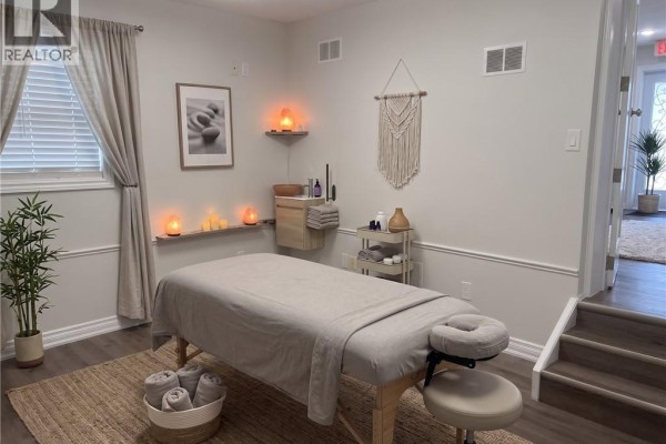 Massage room with a treatment table, salt lamps, macrame wall hanging, and bamboo plant. - 107 Victoria Street S, Kitchener
