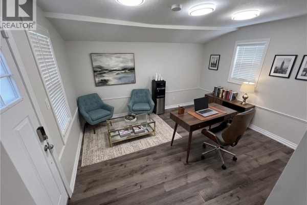 Reception area with two teal chairs, a glass coffee table, and a wooden desk. - 107 Victoria Street S, Kitchener