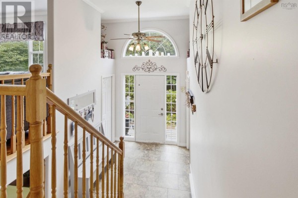 View from the staircase of a foyer with a white front door, sidelights, and a transom window. - 107 Waterstone Run, Lucasville