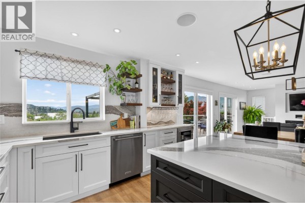 Kitchen window overlooks a valley view, with white cabinetry and stainless steel dishwasher. - 1070 Maccleave Avenue, Penticton