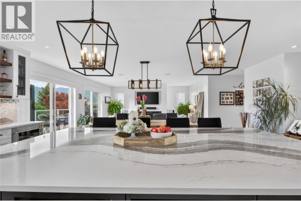 View from kitchen island shows dining area and living room with decorative lighting. - 1070 Maccleave Avenue, Penticton