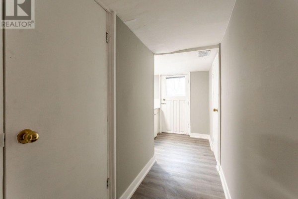 Hallway with light grey walls, white trim, and a door leading to a back exit. - 1070 Shaw Street, Toronto