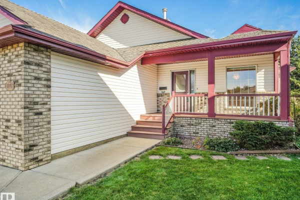 Close-up of the covered front porch with wooden steps, railings, and brick accents. - 10703 6 Av Sw, Edmonton