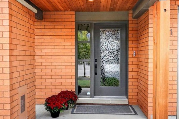 Close-up of the townhouse front door with decorative glass, brick facade, and potted plants. - 1071 Lunar Glow Crescent, Ottawa