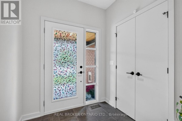 Interior view of the front entrance with a glass door, sidelight, and white double closet doors. - 1071 Lunar Glow Crescent, Ottawa