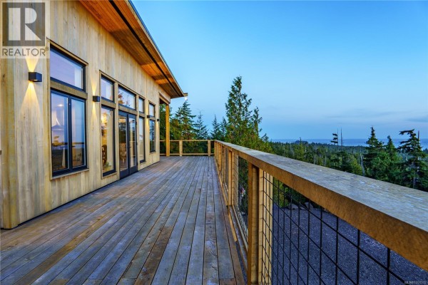Wooden deck with metal railing extending from a house with large windows and ocean view. - 1071 Uplands Close, Ucluelet